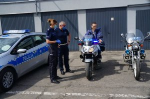 chłopak siedzi na motocyklu obok policjantka, policjant oraz drugi motocykl